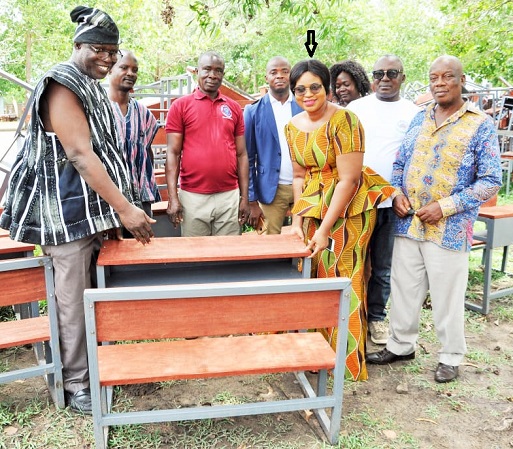 Juliana Kpedekpo (arrowed), the Chief Executive of the Adaklu District Assembly, presenting the desks to Francis Yaw Agbemadi, the District Director of Education, while some members of the district assembly look on